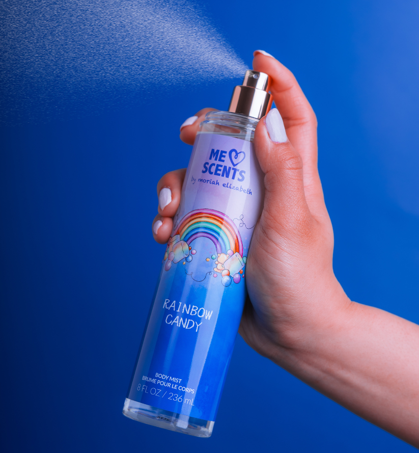 A hand holding the Rainbow Candy Body Mist mid-spritz into the air.