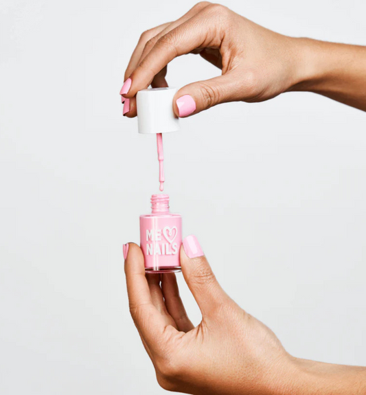 A hand holds the Cotton Candy nail polish while showcasing nails painted in the same shade.